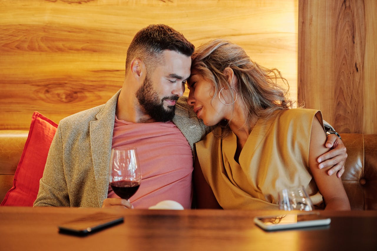 services-01 A couple shares an intimate moment with wine glasses at a cozy restaurant setting.